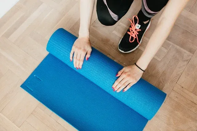 A woman unrolling a yoga mat to start her fitness session
